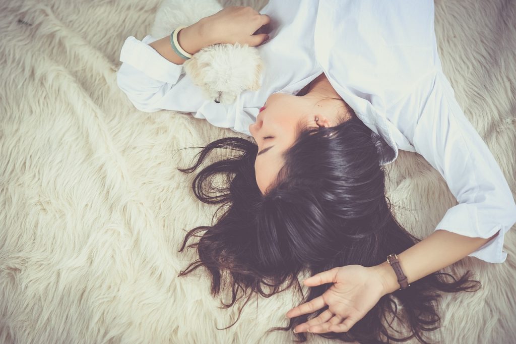 dark haired girl asleep on bed with white shirt clutching a hot water