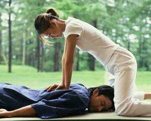lady pressing down on the clients back in thai massage move